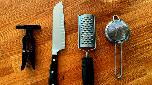 Kitchen tools, a bottle opened, a knife, a zester, a strainer