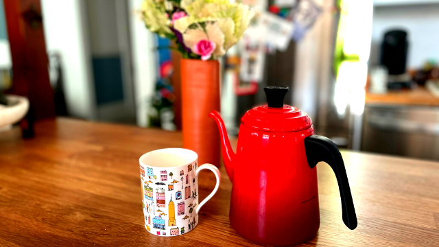 Tea cup and tea pot on a counter with flowers in the background