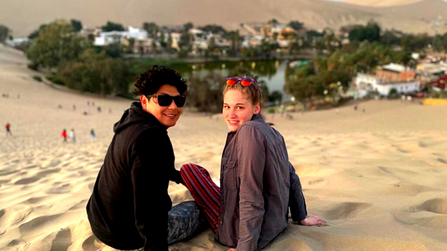 Two people sitting on the sand in Paracas, Peru