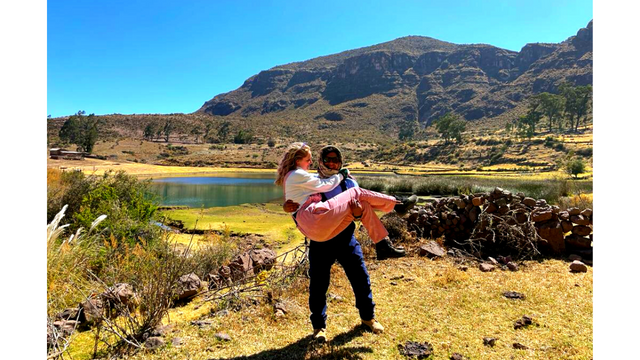 Two people in the mountains in front of a lake