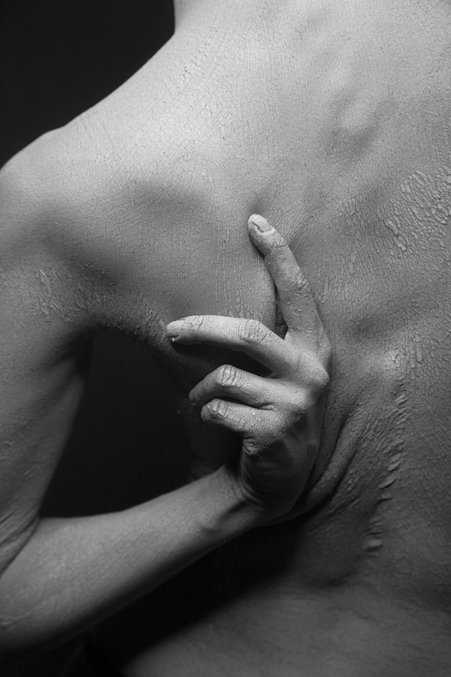 Close-up Of A Person Scratching The Dry And Flaky Skin Of His Back In Black